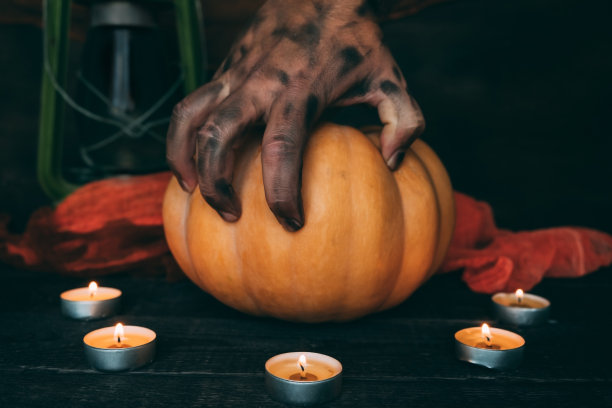 又黑又脏的手放在万圣节南瓜上。图片下载