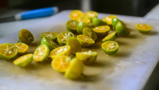 斯里兰卡的一种柑橘，未剥皮，切成两半，撒在切菜板上，准备做新鲜的果汁。丰富的维生素。斯里兰卡多种柑橘，未剥皮，切成两半，撒在砧板上读图片下载
