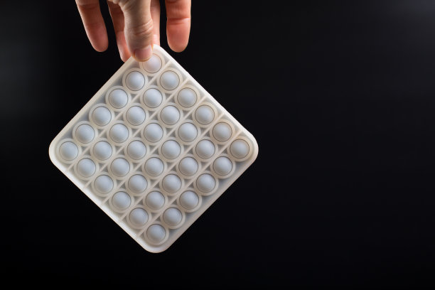 白色硅胶pop it玩具。硅胶泡沫玩具在手。弹出黑色的复制空间。图片下载