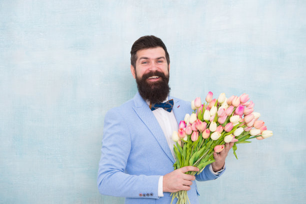 生日问候。给女朋友最好的花。为她花。男人胡子西装领结手持郁金香花束。绅士给她一个浪漫的惊喜。花交付。绅士浪漫的约会图片下载