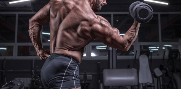 在健身房用哑铃锻炼肱二头肌的强壮运动员照片。健身和健美概念。图片下载