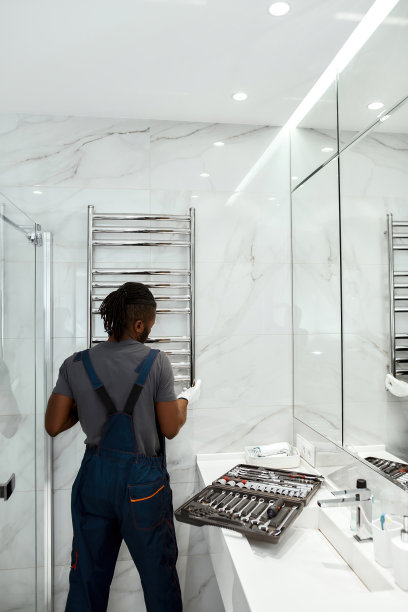 年轻的水管工在现代浴室安装电动毛巾架图片下载