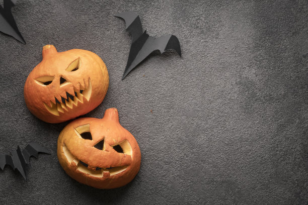 万圣节南瓜flatlay，复制空间照片在黑暗的背景模板。两个吓人的南瓜和杰克的头，一个带着威胁的微笑和邪恶的微笑的模型图片下载