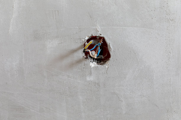 裸露在电线上的电线在一堵灰色的墙上紧锁着。改造的概念。本空间图片下载