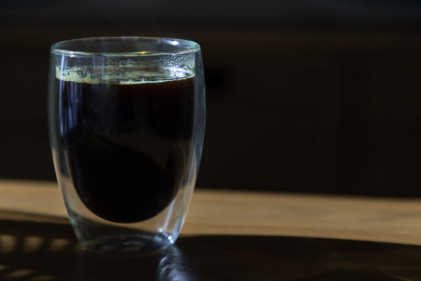 房间里木桌上的玻璃杯里放着黑咖啡。图片下载