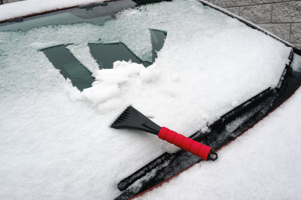 被雪覆盖的汽车挡风玻璃上有刮刀图片下载