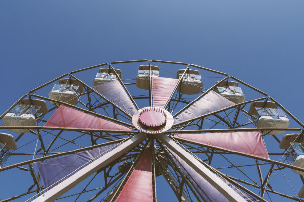 彩色的红色和紫色摩天轮和蓝色的天空背景。图片下载