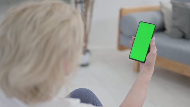 老妇人拿着绿色屏幕的智能手机在运动垫上图片下载