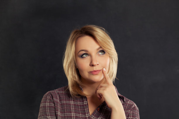 美丽的年轻女子在黑色的背景上思考和向上看图片下载