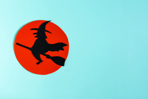 一个戴着帽子坐在扫帚上的黑女巫的影子，映衬着Kopi太空的红色月亮。万圣节广告的模型。图片下载