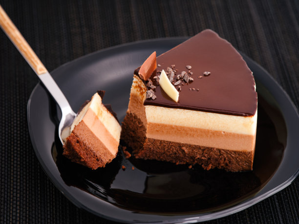 黑色的盘子里放着一块巧克力慕斯蛋糕，然后用勺子放在上面。图片下载