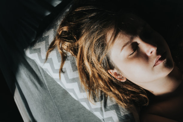 一个白人女人在清晨的阳光下睡觉。图片下载