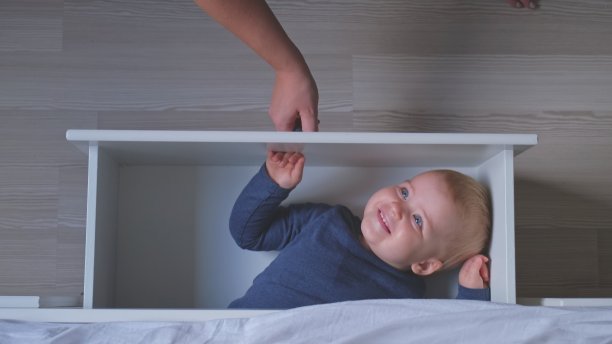 白人女性揭示快乐可爱可爱的白人婴儿蹒跚学步的女孩躲在床抽屉顶部视图图片下载