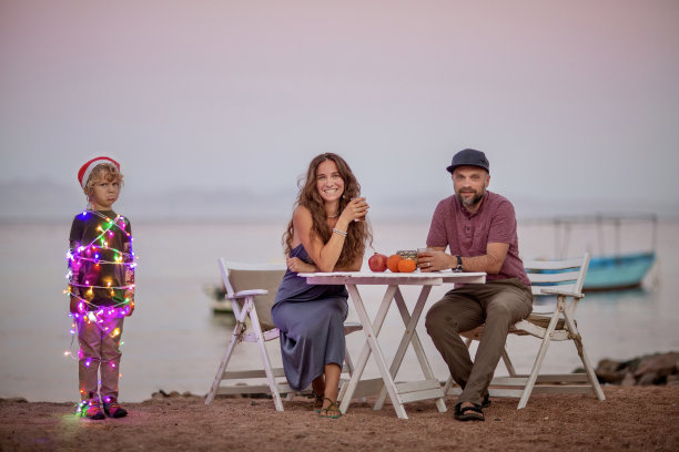 关于圣诞节的有趣照片:父母坐在桌子旁，孩子以圣诞树的形式出现。图片下载