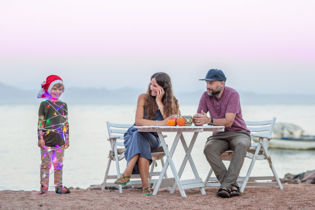 关于圣诞节的有趣照片:父母坐在桌子旁，孩子以圣诞树的形式出现。图片下载