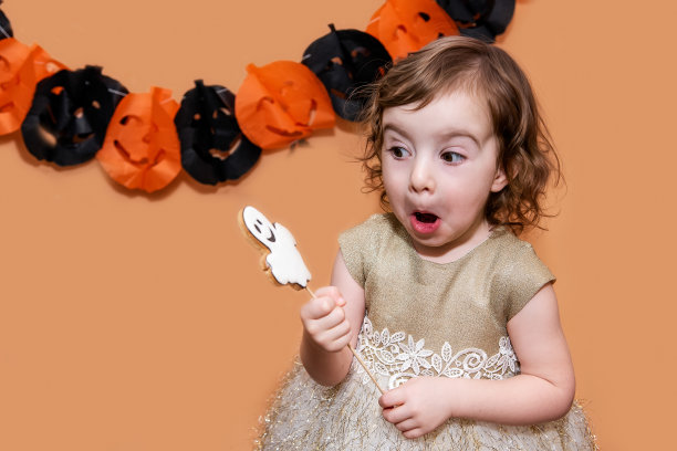 小女孩害怕姜饼形状的幽灵，在一个孤立的背景下玩得很开心图片下载