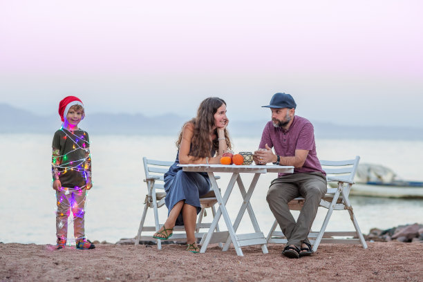 关于圣诞节的有趣照片:父母坐在桌子旁，孩子以圣诞树的形式出现。图片下载