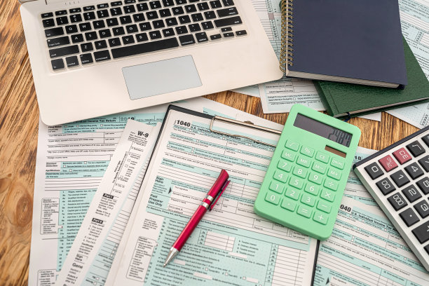木桌上放着一台笔记本电脑、一张带有平板电脑和一支笔的美国报税表图片下载