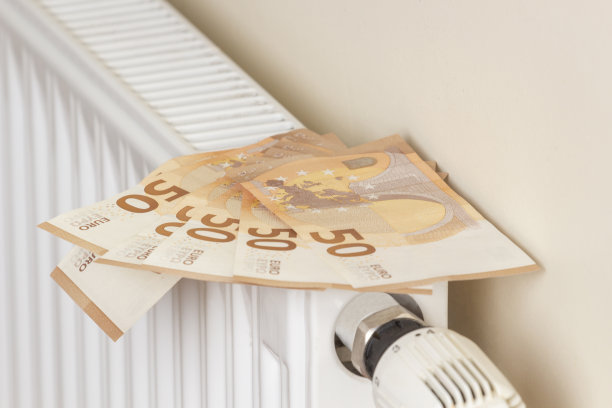 昂贵的供热成本。付账单。欧元钞票上的加热散热器电池与温度调节器在家里图片下载