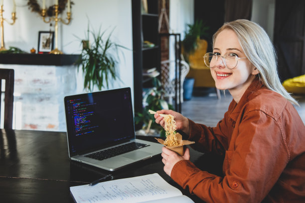 微笑的女开发人员在家庭办公室吃亚洲面条图片下载