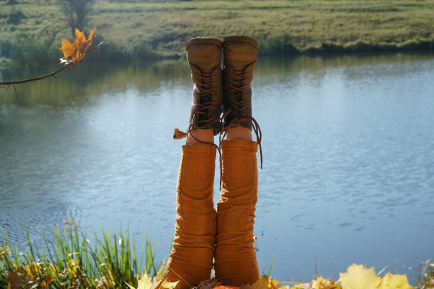 秋天在池塘边的公园里休息。穿着靴子的脚抬了起来图片下载