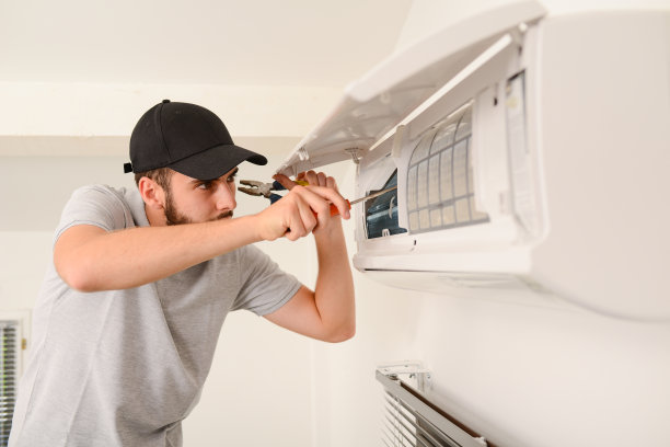 年轻英俊的电工正在客户房内空调系统的室内机上清洗过滤网图片下载