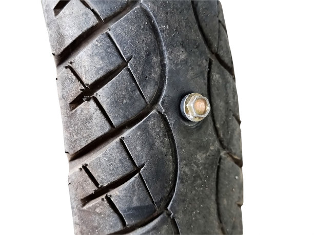 螺丝钉穿摩托车轮胎。后轮近景。孤立的图片下载