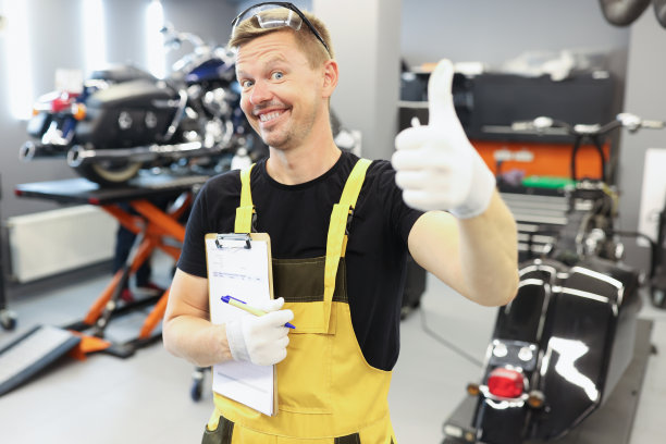 汽车修理工竖起大拇指，在维修车间拿着文件图片下载