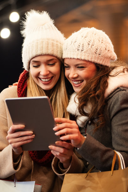 快乐的女性朋友看着数码平板电脑。人们网上购物科技旅游理念图片下载
