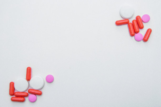 白色和粉色的药片和胶囊放在照片的相反角落，白色背景上留有文字空间图片下载
