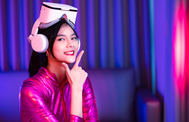 年轻的亚洲女性正在使用虚拟现实耳机。霓虹灯工作室肖像。虚拟现实、模拟、游戏和未来技术的概念。亚洲女人在卧室里玩游戏。图片下载