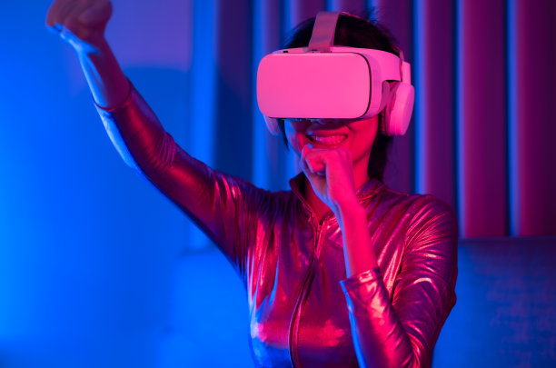 年轻的亚洲女性正在使用虚拟现实耳机。霓虹灯工作室肖像。虚拟现实、模拟、游戏和未来技术的概念。亚洲女人在卧室里玩游戏。图片下载