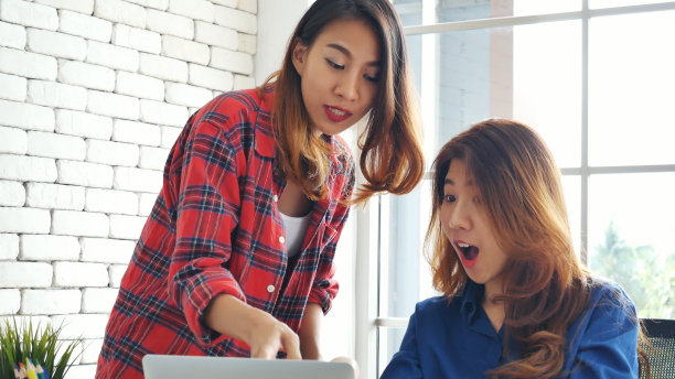 亚洲同事友谊在工作中笑脸相迎。幸福两个女同事一起工作，小组会议在办公桌上。团队业务伙伴与电脑笔记本电脑创业公司图片下载