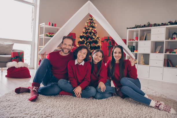 全身照片可爱的家庭儿子女儿舒适地坐在地毯上移动穿红毛衣牛仔裤袜子圣诞夜室内图片下载