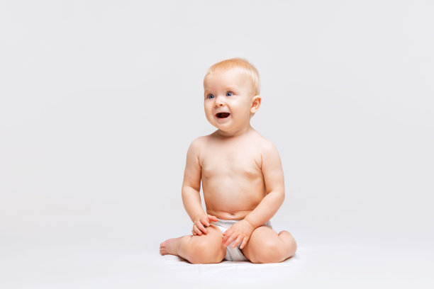 全身肖像小可爱蹒跚学步的女孩，婴儿平静地坐在尿布和玩孤立的白色工作室背景。好奇的图片下载