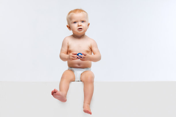 可爱的小女孩的肖像，婴儿平静地坐在和玩孤立的白色工作室背景。图片下载