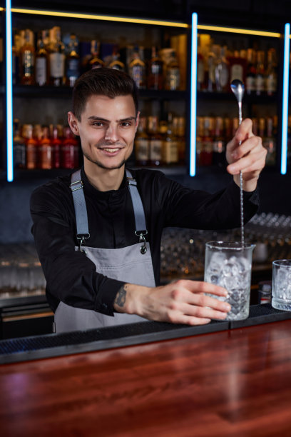 酒吧服务员用勺子在鸡尾酒杯里搅拌冰块图片下载