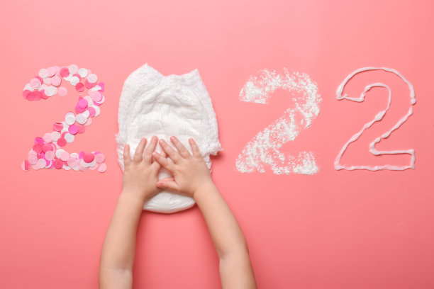 数字2022用五彩纸屑、尿布、滑石粉和婴儿霜排列在粉红色的背景上。图片下载