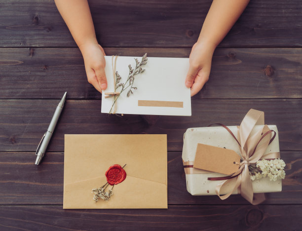 木制桌子背景上的手女孩手持卡片和工艺礼盒上面图片下载