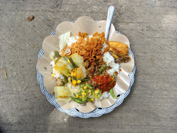 用塑料盘子盛着拌有印尼特色菜的米饭图片下载