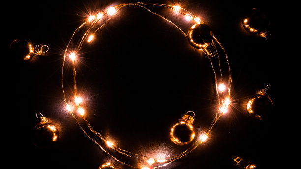 圣诞灯花环。金光花环装饰，金色灯泡孤立在黑色为圣诞派对装饰背景。冬季节日作文与复制空间。图片下载