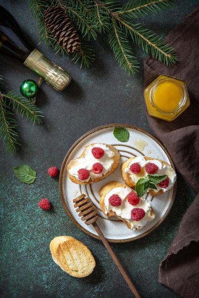 圣诞晚餐，节日菜单。传统的意大利开胃菜意式烤面包配以奶油芝士、覆盆子和蜂蜜，是圣诞餐桌上的美味佳肴。俯视图平面铺设。图片下载