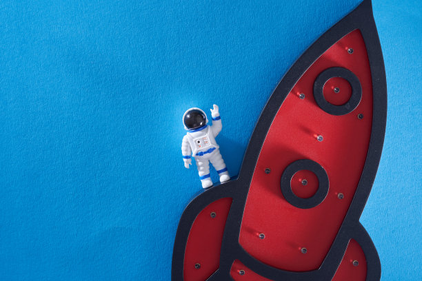 蓝色背景下的太空火箭和玩具宇航员。图片下载