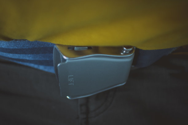 飞机安全带扣在低调的黑暗穆迪照片。艺术或不同的照片，男人系着安全带与扣在他的腰带线。图片下载