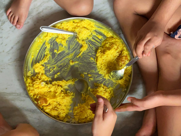 特写照片:三个无法辨认的印度孩子坐在地板上，围着塔利(金属盘子)吃着混合蔬菜和米饭，从高处看图片下载