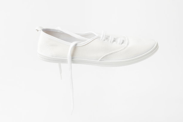 白色帆布花边男女通用帆布鞋在相同的颜色背景与复制空间。经典休闲运动鞋图片下载