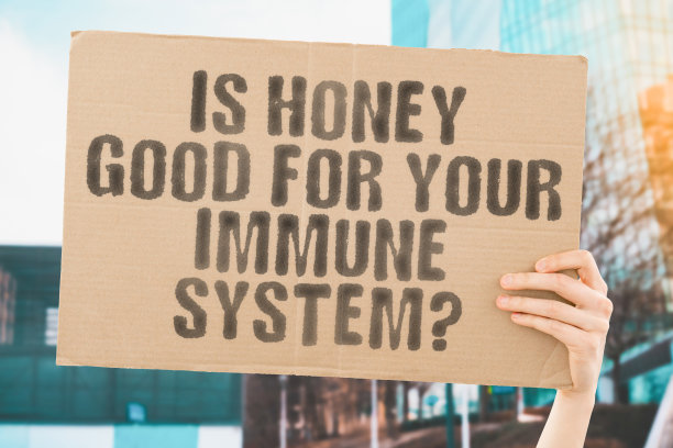 “蜂蜜对免疫系统有好处吗?”一名男子手里拿着一面背景模糊的横幅。补救措施。药丸。治疗。医疗保健。疾病。流感。感染。营养。帮助图片下载