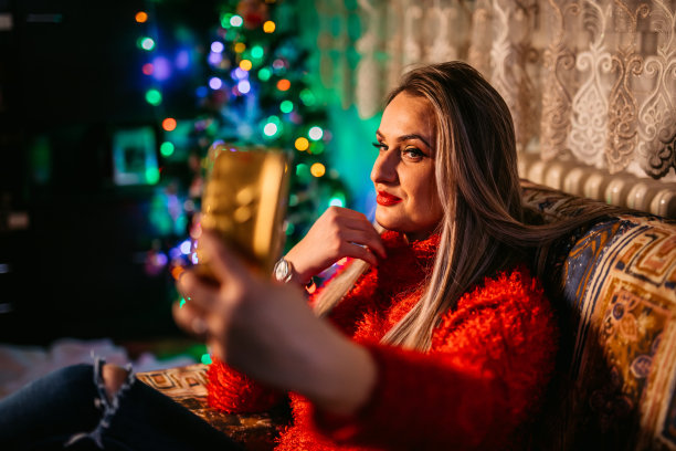 一个女人在圣诞树旁自拍图片下载