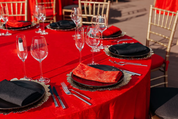 宴会用黑、红、金三色餐桌。优雅豪华的晚餐安排:装饰，桌布，盘子，玻璃杯，餐巾，餐具。主题生日或婚礼派对庆祝图片下载