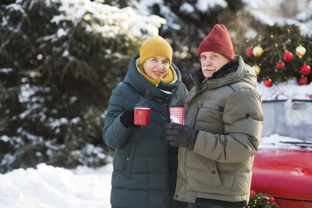 老夫妇们穿着暖和的冬衣，端着茶站在街上。圣诞快乐!图片下载